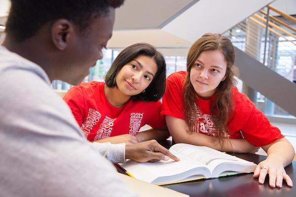 Three LU students studying a textbook together.